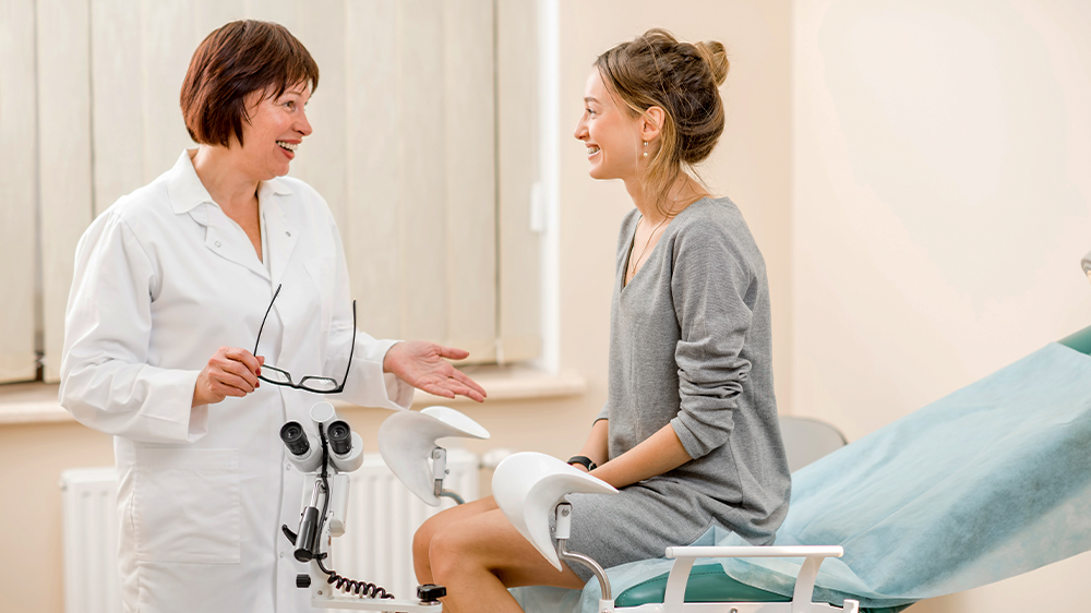Chatting with a smiling doctor, a patient presents her list of questions to ask the gynecologist when trying to get pregnant.